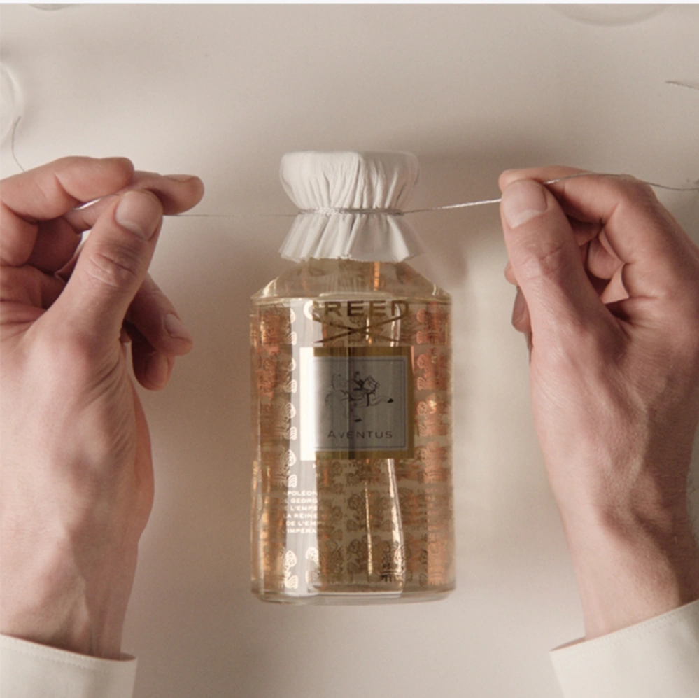 Perfumy Creed są starannie pakowane, a nad butelką widoczna jest biała wstążka.