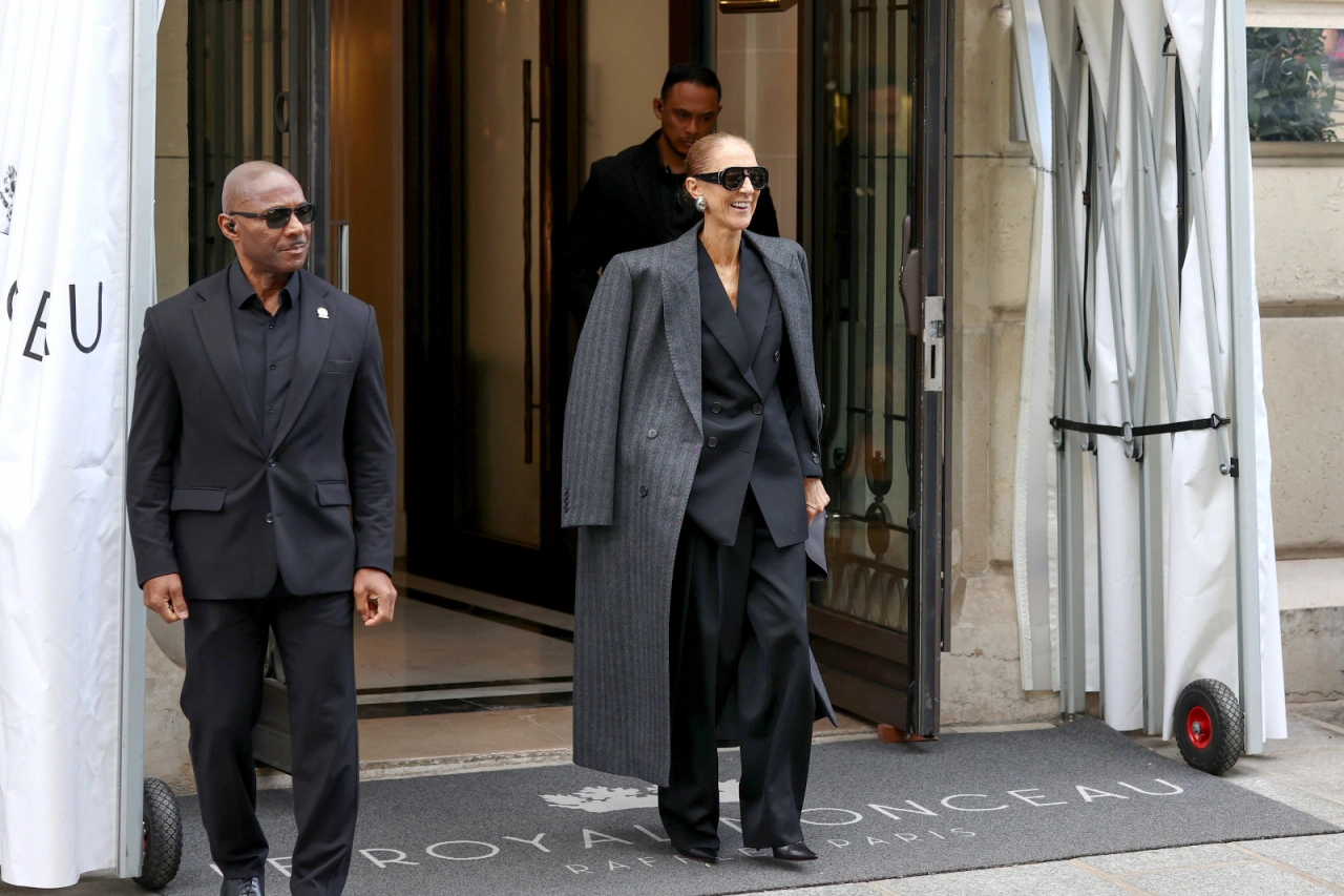 Celine Dion w Paryżu, wychodząc z luksusowego hotelu, w eleganckim stroju z towarzyszącymi osobami.