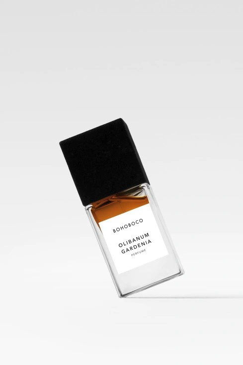 Flakon perfum z ciemnym korkiem, z etykietą "Olibanum Gardenia". Pojemność nieokreślona, intensywna barwa płynu.